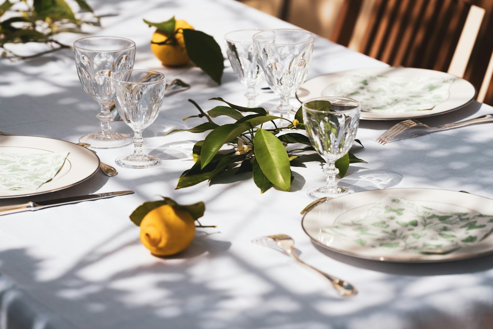 Sunlit table with crystal glasses, lemons and green leaves