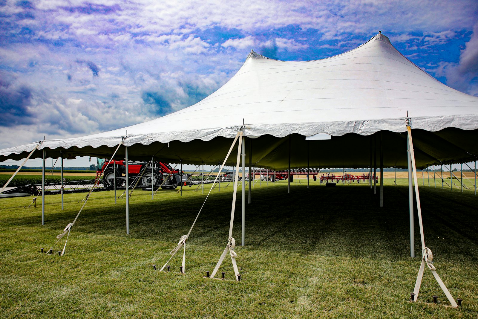 A white sailcloth tent with a scalloped valance standing on a green lawn