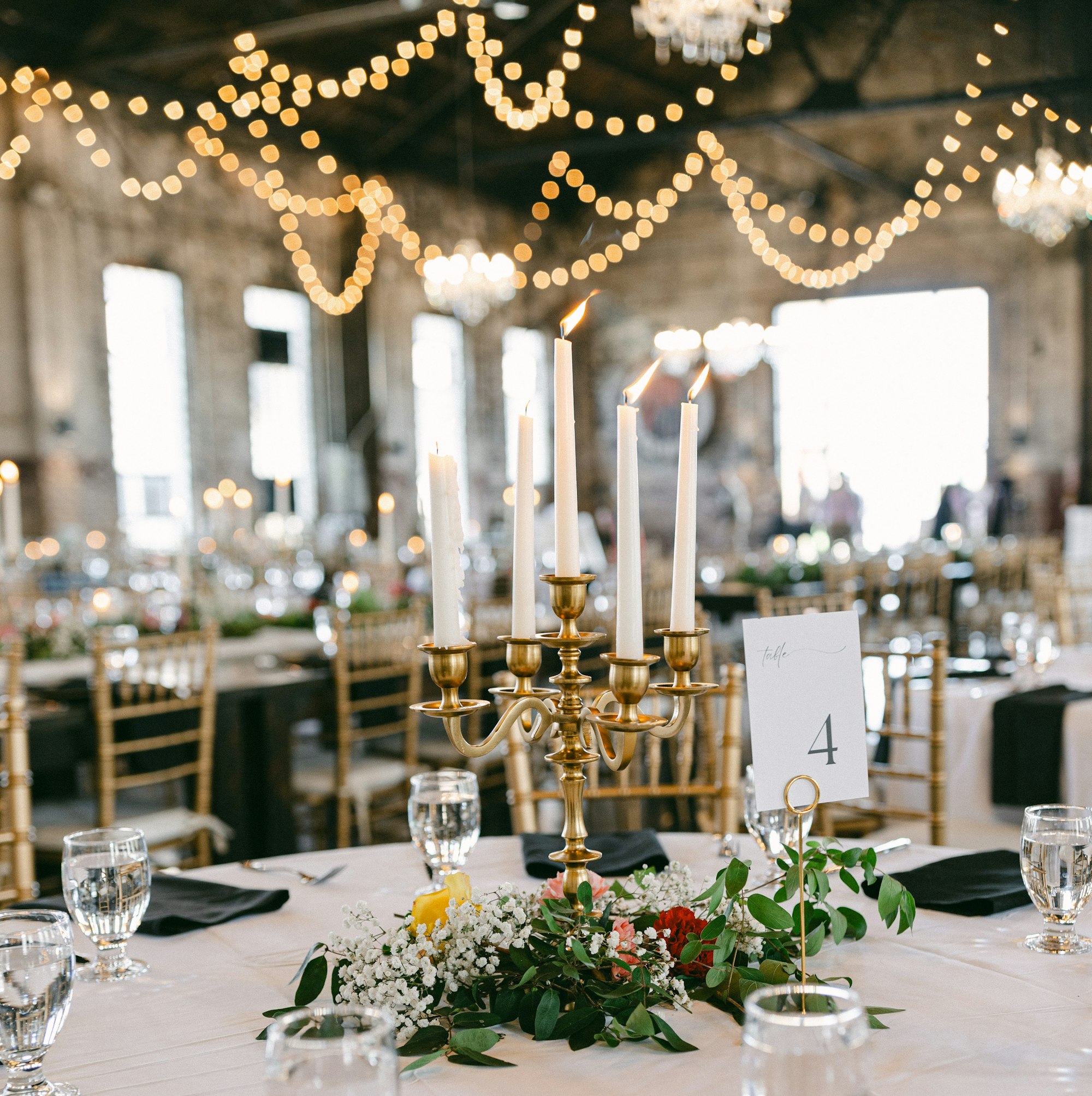 A reception hall with brass candelabras and strings of warm lights