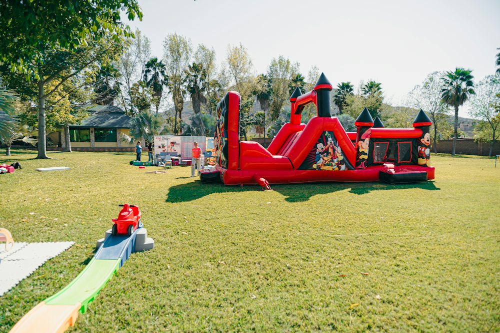 A red inflatable castle bounce house on a lawn