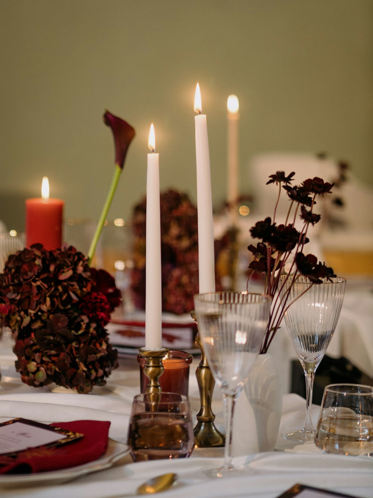 Taper candles and deep red hydrangeas on a dressed table