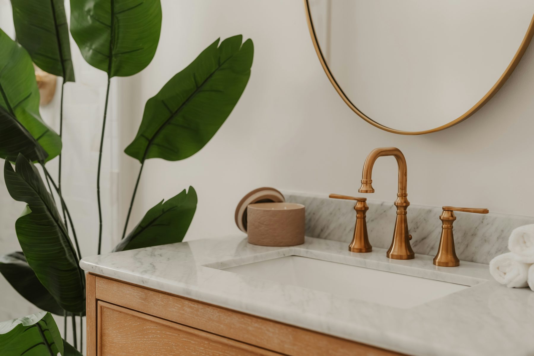 A marble vanity with a brass tap and green leaves