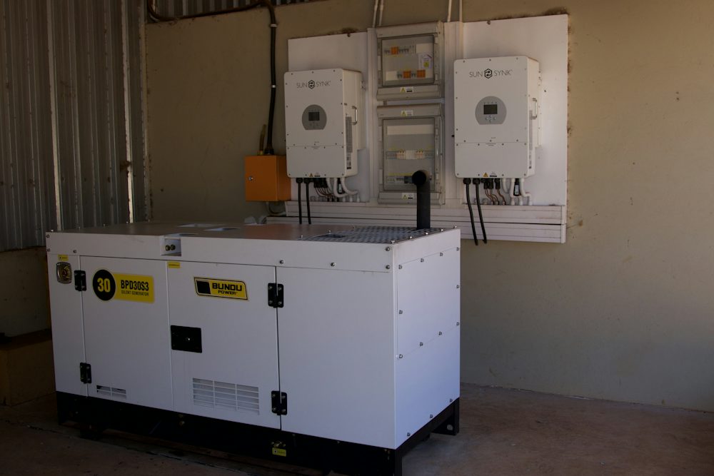 A white generator beside wall-mounted power equipment